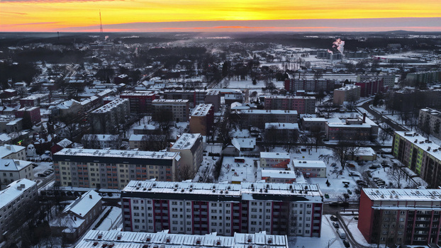 Aerial view of a snow covered town with residential apartment buildings and rooftops during a vibrant golden hour sunset in Latvia. Aerial view of a snow covered town with residential apartment buildings and rooftops during a vibrant golden hour sunset in Latvia.