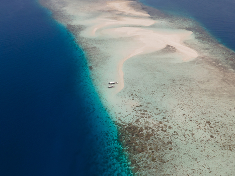 Aerial view of Pasir Timbul Mansuar sandbar surrounded by turquoise shallow waters and deep blue sea with small boats docked on the white sand. Raja Ampat Papua Barat Indonesia. Aerial view of Pasir Timbul Mansuar sandbar surrounded by turquoise shallow waters and deep blue sea with small boats docked on the white sand. Raja Ampat Papua Barat Indonesia.