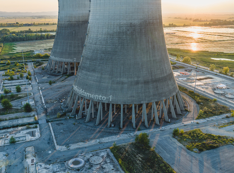 Trino Piedmont Italy 12 September 2026 Aerial view of abandoned power plant cooling towers at sunset surrounded by solar panels and industrial infrastructure.