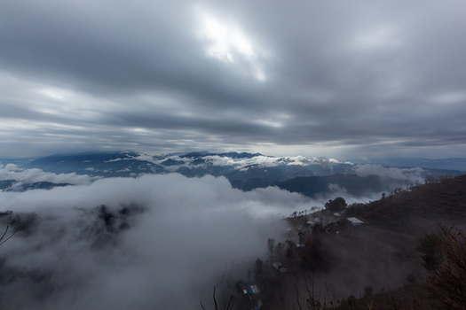 View of a landscape where the mountain peaks pierce through a thick blanket of clouds with scattered homes nestled on the slopes Muzaffarabad Azad Kashmir Pakistan. View of a landscape where the mountain peaks pierce through a thick blanket of clouds with scattered homes nestled on the slopes Muzaffarabad Azad Kashmir Pakistan.