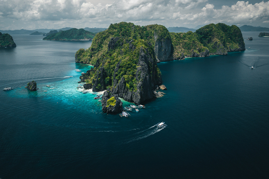Aerial view of dramatic limestone cliffs turquoise waters and traditional outrigger boats in El Nido Mimaropa Philippines. Aerial view of dramatic limestone cliffs turquoise waters and traditional outrigger boats in El Nido Mimaropa Philippines.