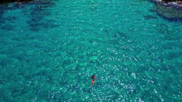 Aerial view of a person swimming in turquoise waters Greece.