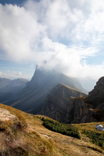 Aerial view of the Dolomites with rugged mountain peaks partially obscured by clouds rocky slopes and grassy terrain in Rocca Pietore Veneto Italy.