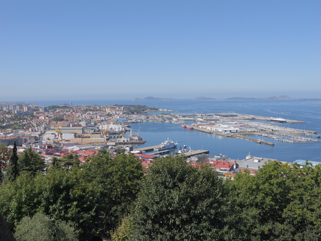 View of the port of Vigo with industrial harbor facilities docked ships and urban buildings under a clear blue sky in Vigo Pontevedra Spain.