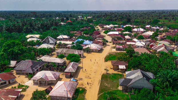Aerial view of the village of Abua featuring scattered houses with metal rooftops and dirt roads surrounded by lush green vegetation and palm trees Abua Rivers Nigeria. Aerial view of the village of Abua featuring scattered houses with metal rooftops and dirt roads surrounded by lush green vegetation and palm trees Abua Rivers Nigeria.
