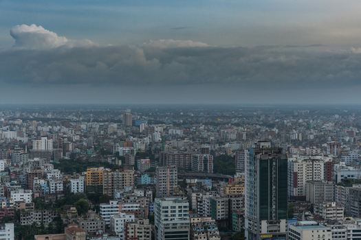 Dhaka Bangladesh 30 June 2025 Aerial view of the dense urban skyline of Dhaka featuring a mix of mid rise and high rise buildings under a dramatic overcast sky.