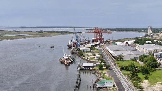 Aerial view of a busy port with cranes ships industrial buildings calm water and green marsh Fernandina Beach Florida United States. Aerial view of a busy port with cranes ships industrial buildings calm water and green marsh Fernandina Beach Florida United States.
