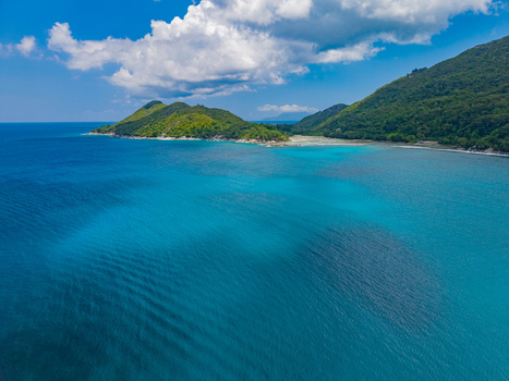 Aerial view of turquoise waters meeting lush green hills under a bright sky creating a breathtaking tropical paradise Port Launay Mahe Island Seychelles. Aerial view of turquoise waters meeting lush green hills under a bright sky creating a breathtaking tropical paradise Port Launay Mahe Island Seychelles.