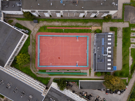 Aerial view of a red basketball court surrounded by school buildings and green spaces in Gdansk Poland. Aerial view of a red basketball court surrounded by school buildings and green spaces in Gdansk Poland.