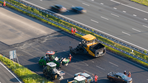 Waardenburg Netherlands 09 May 2026 Aerial view of asphalt paving machinery and road workers on a highway during maintenance with blurred traffic passing by. Waardenburg Netherlands 09 May 2026 Aerial view of asphalt paving machinery and road workers on a highway during maintenance with blurred traffic passing by.