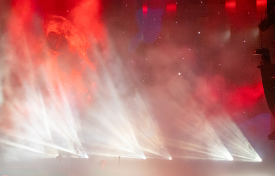 View of stage lighting beams cutting through haze with a red background at a concert in Nyon Vaud Switzerland.