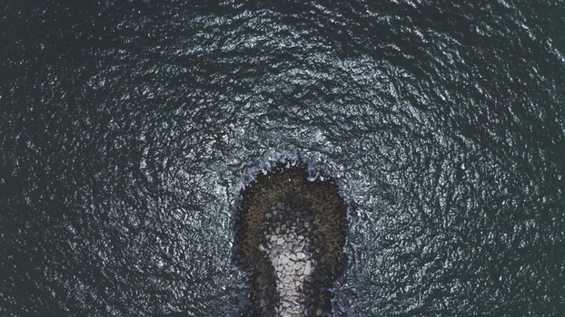 Aerial view of a stone breakwater jetty surrounded by deep blue rippling ocean water at Lekki Lagos Nigeria. Aerial view of a stone breakwater jetty surrounded by deep blue rippling ocean water at Lekki Lagos Nigeria.