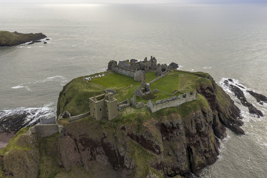 Aerial view of the medieval ruins of Dunnottar Castle on a rocky headland overlooking the North Sea in Stonehaven Scotland United Kingdom. Aerial view of the medieval ruins of Dunnottar Castle on a rocky headland overlooking the North Sea in Stonehaven Scotland United Kingdom.