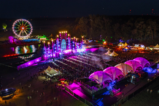Herzogenaurach Germany 22 July 2022 Aerial view of the Open Beatz Festival featuring a massive illuminated main stage a colorful Ferris wheel and a large crowd of people at night. Herzogenaurach Germany 22 July 2022 Aerial view of the Open Beatz Festival featuring a massive illuminated main stage a colorful Ferris wheel and a large crowd of people at night.