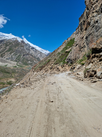 View of Penzi La road winding through the rugged rocky mountain landscape of the Zanskar valley with snow capped peaks in the distance under a clear blue sky Zanskar Ladakh India.