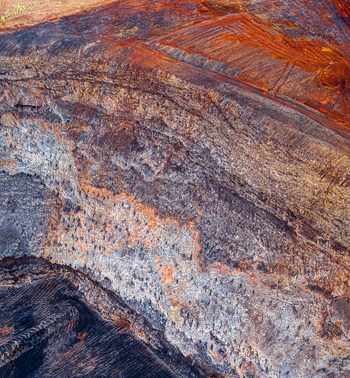 Aerial view of an open pit mine showcasing layered rock formations and mineral deposits in the rugged terrain of Iceland. Aerial view of an open pit mine showcasing layered rock formations and mineral deposits in the rugged terrain of Iceland.
