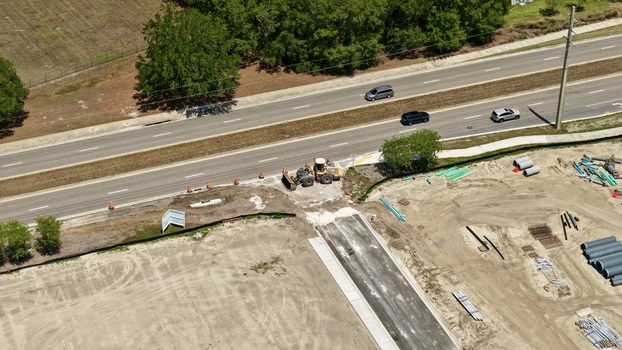 Aerial view of the Foundry Lane construction site with a front loader and building materials next to a highway in World Golf Village Florida United States.