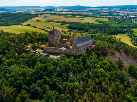 Aerial view of Tocnik Castle surrounded by dense green forests and rolling hills under a clear blue sky in Tocnik Stredocesky kraj Czechia. Aerial view of Tocnik Castle surrounded by dense green forests and rolling hills under a clear blue sky in Tocnik Stredocesky kraj Czechia.