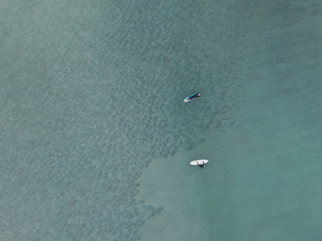 Aerial view of two surfers on surfboards in the clear turquoise waters of the Lofoten archipelago in Svolvaer Nordland Norway.