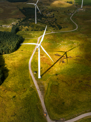Aerial view of Hog Jaeren vindkraftverk wind turbines set in rolling green hills with gravel access roads and long shadows cast across the terrain in Ha Municipality Rogaland Norway. Aerial view of Hog Jaeren vindkraftverk wind turbines set in rolling green hills with gravel access roads and long shadows cast across the terrain in Ha Municipality Rogaland Norway.