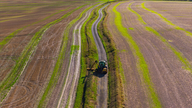 Aerial view of a tractor trimming hedges along a narrow country road winding through agricultural fields at Pepperbox Hill. Salisbury England United Kingdom. Aerial view of a tractor trimming hedges along a narrow country road winding through agricultural fields at Pepperbox Hill. Salisbury England United Kingdom.