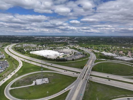 Aerial view of a highway interchange and a large commercial building surrounded by green fields and suburban landscape under a cloudy sky in Columbus Ohio United States. Aerial view of a highway interchange and a large commercial building surrounded by green fields and suburban landscape under a cloudy sky in Columbus Ohio United States.