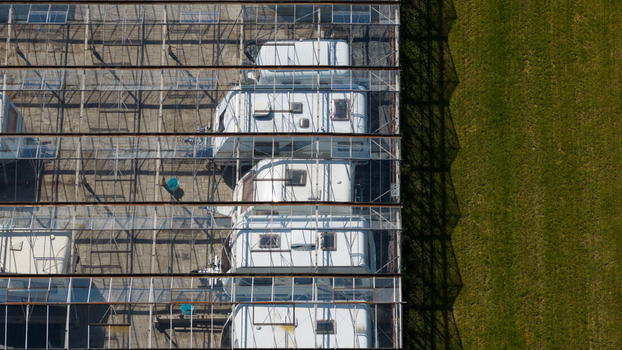 Aerial view of Caravanstalling Klijn with white caravans parked inside a large glass roofed storage facility next to a green field in Alkmaar Noord Holland Netherlands. Aerial view of Caravanstalling Klijn with white caravans parked inside a large glass roofed storage facility next to a green field in Alkmaar Noord Holland Netherlands.