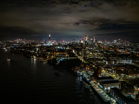 Aerial view of the illuminated London skyline at night featuring the Shard and the River Thames winding through the urban landscape of London England United Kingdom. Aerial view of the illuminated London skyline at night featuring the Shard and the River Thames winding through the urban landscape of London England United Kingdom.