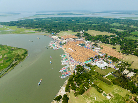 Aerial view of boats docked along the muddy riverbank contrasting with the lush green landscape Charmonai Barisal Division Bangladesh. Aerial view of boats docked along the muddy riverbank contrasting with the lush green landscape Charmonai Barisal Division Bangladesh.