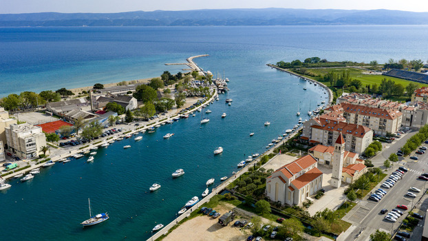 Aerial view of the Cetina river mouth with moored boats the historic church of St. Peter and the Adriatic Sea in Omis Split Dalmatia County Croatia. Aerial view of the Cetina river mouth with moored boats the historic church of St. Peter and the Adriatic Sea in Omis Split Dalmatia County Croatia.