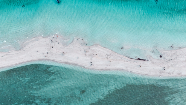 Aerial view of Pulau Derawan featuring turquoise waters coral reefs and wooden stilt houses over the sea in Pulau Derawan East Kalimantan Indonesia. Aerial view of Pulau Derawan featuring turquoise waters coral reefs and wooden stilt houses over the sea in Pulau Derawan East Kalimantan Indonesia.