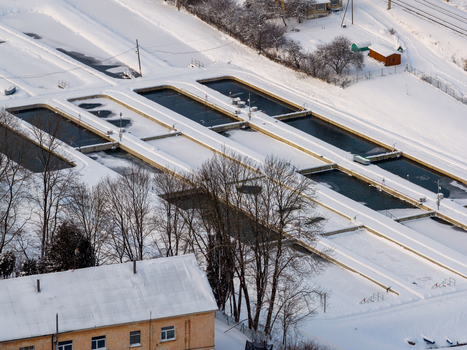 Aerial view of rectangular fish farm pools surrounded by a thick layer of white snow and bare winter trees in Lithuania. Aerial view of rectangular fish farm pools surrounded by a thick layer of white snow and bare winter trees in Lithuania.