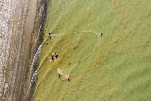 Aerial view of fishermen using a large net in the shallow coastal waters of Kuakata Barisal Division Bangladesh. Aerial view of fishermen using a large net in the shallow coastal waters of Kuakata Barisal Division Bangladesh.