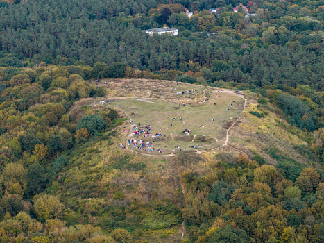 Aerial view of Drachenberg hill surrounded by dense forest and green landscape with people relaxing on the grassy slopes in Berlin Berlin Germany.