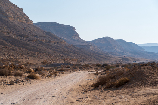 View of sun drenched rugged terrain with a winding dirt road cutting through the arid landscape under a clear sky Wadi Degla Protectorate Cairo Egypt. View of sun drenched rugged terrain with a winding dirt road cutting through the arid landscape under a clear sky Wadi Degla Protectorate Cairo Egypt.