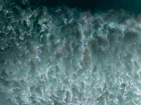 Aerial view of turquoise ocean waves with white foam and two surfers paddling in the water in Whangamata Coromandel New Zealand. Aerial view of turquoise ocean waves with white foam and two surfers paddling in the water in Whangamata Coromandel New Zealand.