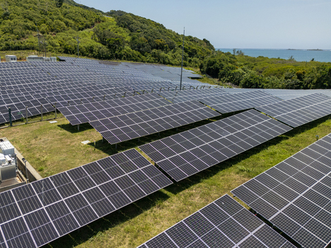 Aerial view of a large solar panel farm situated on a lush green hillside overlooking the Caribbean Sea in Guanaja Bay Islands Department Honduras.