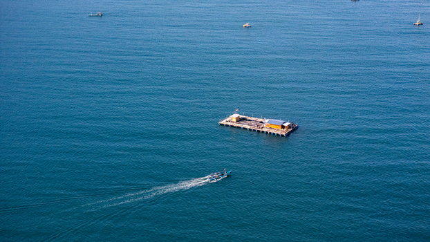 Aerial view of a floating fish farm platform on the calm blue waters of Pantai Karanggongso in Watulimo East Java Indonesia. Aerial view of a floating fish farm platform on the calm blue waters of Pantai Karanggongso in Watulimo East Java Indonesia.