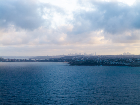 Aerial view of the coastline and residential area of Dee Why with the distant Sydney skyline under a cloudy sky in Dee Why New South Wales Australia. Aerial view of the coastline and residential area of Dee Why with the distant Sydney skyline under a cloudy sky in Dee Why New South Wales Australia.
