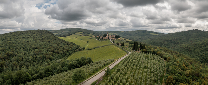 Aerial view of the village of Passignano nestled among rolling hills lush vineyards and olive groves under a cloudy sky in Passignano Toscana Italy. Aerial view of the village of Passignano nestled among rolling hills lush vineyards and olive groves under a cloudy sky in Passignano Toscana Italy.