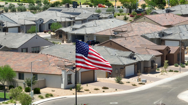 Aerial view of a residential neighborhood in Glendale featuring suburban houses with tiled roofs and a prominent American flag waving in the foreground Glendale Arizona United States. Aerial view of a residential neighborhood in Glendale featuring suburban houses with tiled roofs and a prominent American flag waving in the foreground Glendale Arizona United States.