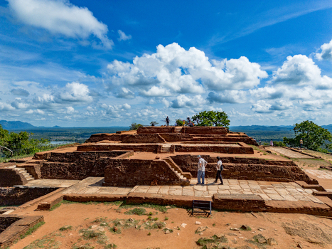 Aerial view of the ancient ruins of Sigiriya Lion Rock featuring stone foundations brick structures and tourists on the summit under a blue sky in Sigiriya Central Province Sri Lanka. Aerial view of the ancient ruins of Sigiriya Lion Rock featuring stone foundations brick structures and tourists on the summit under a blue sky in Sigiriya Central Province Sri Lanka.