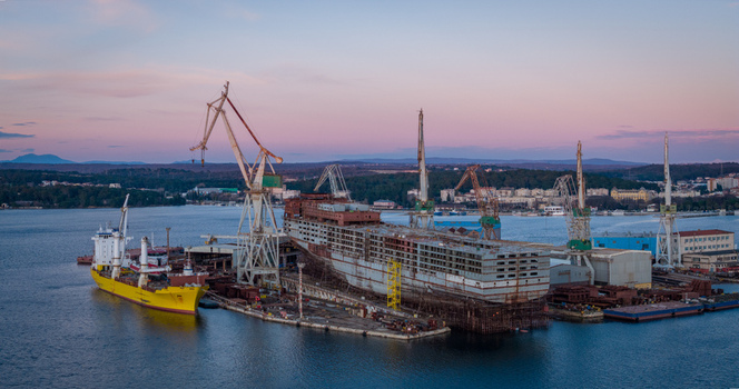 Aerial view of Uljanik Shipyard with large cranes and a ship under construction in the harbor at sunset in Pula Croatia. Aerial view of Uljanik Shipyard with large cranes and a ship under construction in the harbor at sunset in Pula Croatia.