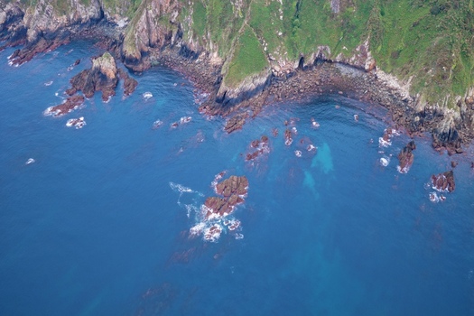 Aerial view of the rugged rocky coastline with green cliffs and turquoise ocean water in Cudillero Asturias Spain. Aerial view of the rugged rocky coastline with green cliffs and turquoise ocean water in Cudillero Asturias Spain.