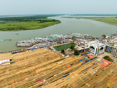 Aerial view of vast golden mats drying under the sun contrasting with the winding river and the green mosque Charmonai Barisal Division Bangladesh. Aerial view of vast golden mats drying under the sun contrasting with the winding river and the green mosque Charmonai Barisal Division Bangladesh.