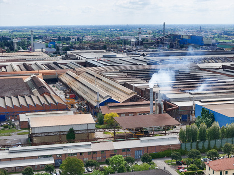 Aerial view of the vast industrial complex and steel plant with smoking chimneys and warehouse rooftops in Dalmine Lombardy Italy. Aerial view of the vast industrial complex and steel plant with smoking chimneys and warehouse rooftops in Dalmine Lombardy Italy.