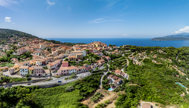 Aerial view of the historic town with its colorful buildings surrounding green hills and coastal landscape in Capoliveri Tuscany Italy.