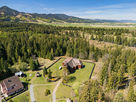 Aerial view of the Wooden Articular Church of Svaty Kriz surrounded by a green lawn and dense evergreen forest with mountains in the distance Svaty Kriz Zilinsky kraj Slovakia.