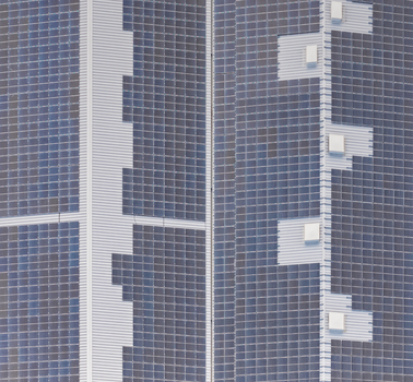 Aerial view of a massive rooftop photovoltaic installation on an industrial warehouse with a dense geometric pattern of solar panels in Loriol sur Drome Auvergne Rhone Alpes France.