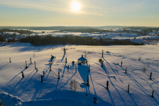 Aerial view of the Hill of Angels with wooden sculptures and a gazebo on a snow covered field under a bright winter sun in Traku rajonas Vilniaus apskritis Lithuania. Aerial view of the Hill of Angels with wooden sculptures and a gazebo on a snow covered field under a bright winter sun in Traku rajonas Vilniaus apskritis Lithuania.